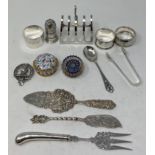 A silver toast rack, marks rubbed, three silver napkin rings, and other items