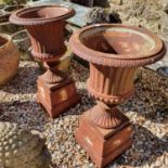 A pair of cast metal campagna form garden urns, on square bases, 69 cm high