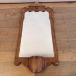 A George III style walnut and giltwood wall mirror, with a shell finial, and base with candle stand,