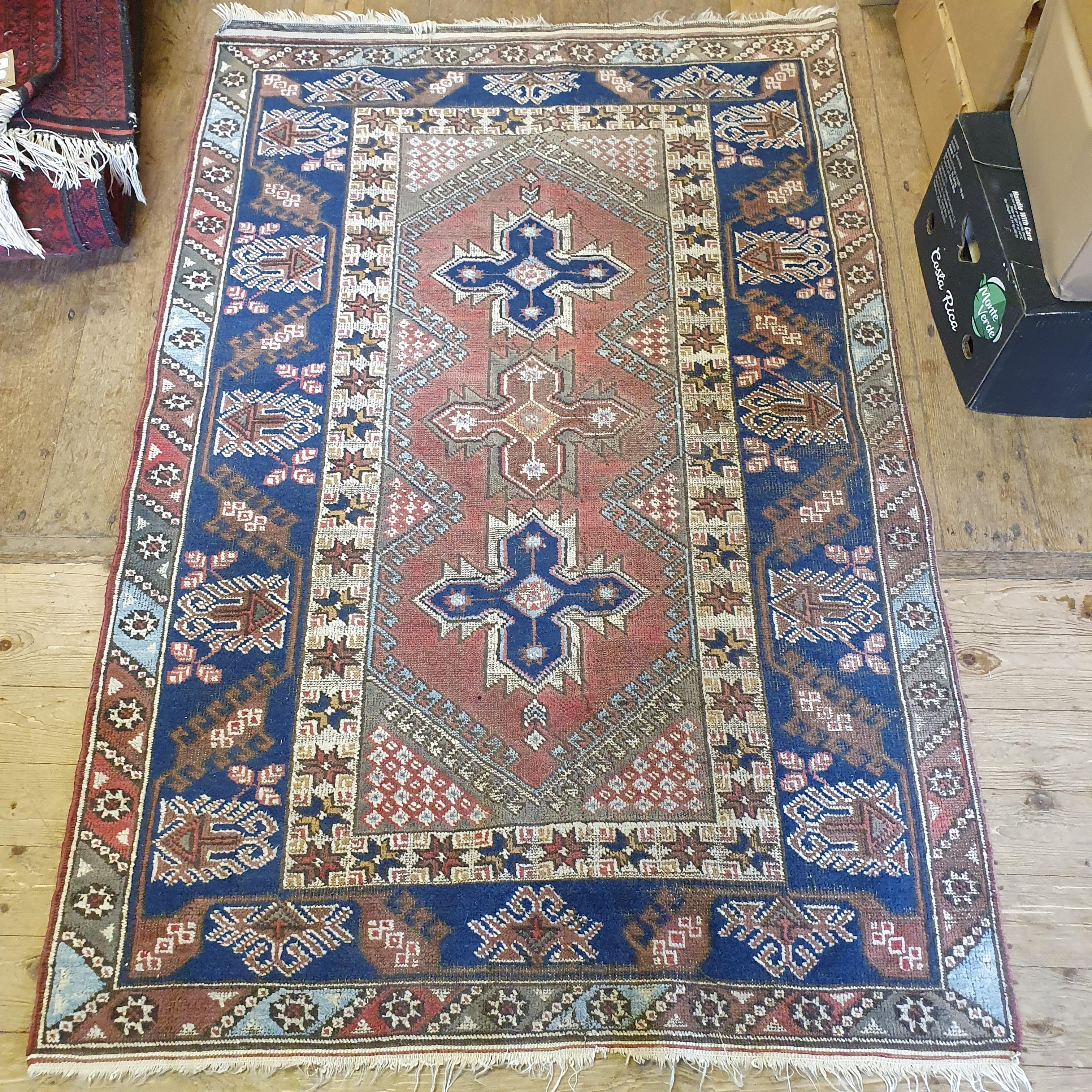 A Persian red ground rug, main blue boarder, the centre with three geometric medallions, 187 x 124