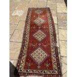 A Persian red ground runner, with multiple borders, centre with four lozenge shaped medallions,