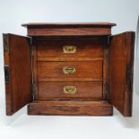 An early 20th century oak desk top cabinet, the two doors to reveal three drawers, on a plinth base,