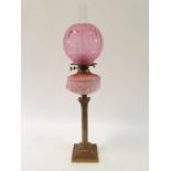 An oil lamp, with an acid etched glass shade, a pink glass well, and on brass base in the form of