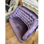 A small settee, upholstered in purple fabric, on ebonised turned front legs