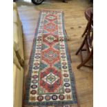 A Persian type red ground runner multiple borders centre with repeating lozenge shape medallions,