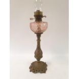 An oil lamp, with a pink glass well, on a brass base decorated flowers, 82 cm high No shade, surface