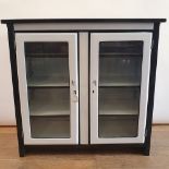 A white and black enamel cabinet, having two glazed doors, 96 cm wide
