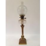 An oil lamp, with an acid etched glass shade, a clear glass well on a brass base in the form of a