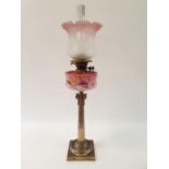 An oil lamp, with an acid etched glass shade, a pink glass well painted flowers, on a silver