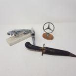 A Mercedes-Benz three pointed star bonnet emblem, other emblems, a pocket knife, a bag of coins
