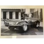 A monochrome photograph, Steve McQueen, in Jaguar XKSS, 41 cm high x 63 cm wide, two other