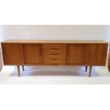 A 1970s teak sideboard, with four central drawers, flanked by four sliding doors on turned