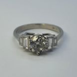 A platinum and diamond solitaire ring, with baguette diamond shoulders, ring size L Total diamond