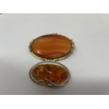 An amber and silver brooch and a orange stone brooch in gilt metal mount (2)