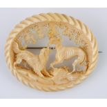 A late 19th/early 20th century carved ivory brooch, decorated two fighting dogs Small losses visible