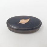 An early 19th century horn oval snuff box, the top inset with a yellow metal leaf, 8 cm wide Hinge