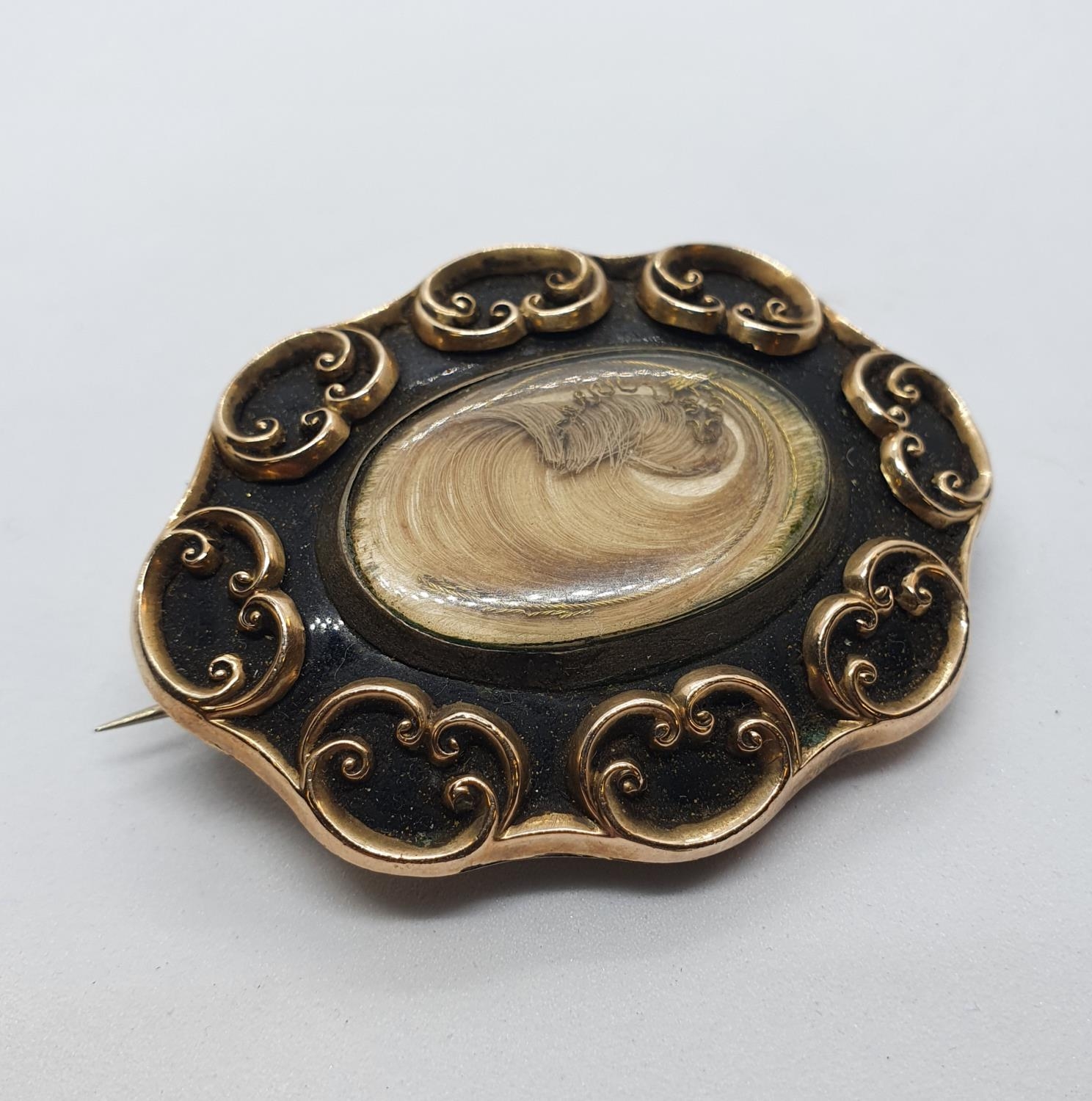 A Victorian yellow coloured metal and black enamel memorial brooch, inset with a lock of hair All in
