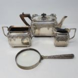 A magnifying glass, with a silver colour metal handle, a silver plated three piece tea service, an