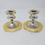 A pair of George V silver and yellow enamel candlesticks, Birmingham 1930, 9 cm high Filled, small