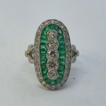 A platinum, emerald and diamond oval ring, ring size L Centre diamonds old cut, surrounded by