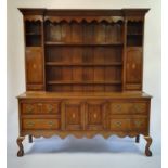 An 18th century style oak dresser, the top with shelves, two cupboard doors and two drawers, the