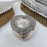 A George V silver heart shaped box, three silver backed brushes, a napkin ring, a sifting spoon