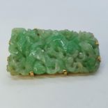 A carved jade brooch, in yellow metal mount 47mm by 22mm a deepest point, 6.2 mm deep, 19.4 g no