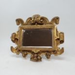 A carved wood and gilt mirror, with lion's head finial, 27 x 23 cm, a carved giltwood wall mount, 25