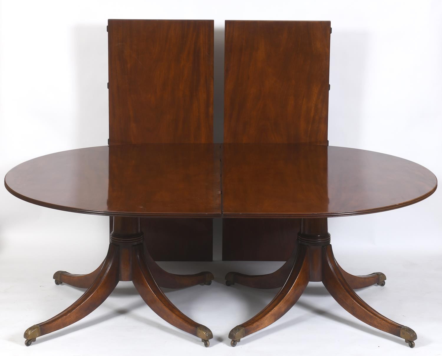 A George III style mahogany twin pillar dining table, on column supports to splayed legs, with two