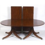 A George III style mahogany twin pillar dining table, on column supports to splayed legs, with two