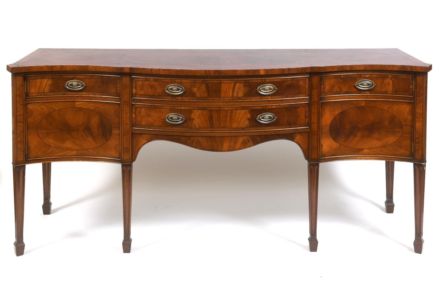 A George III style mahogany serpentine sideboard, having two central drawers flanked by a single