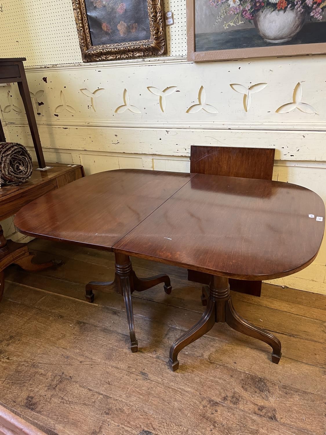 A George III style mahogany twin pillar, tilt top dining table, inset an extra leaf, 132 x 95 cm,