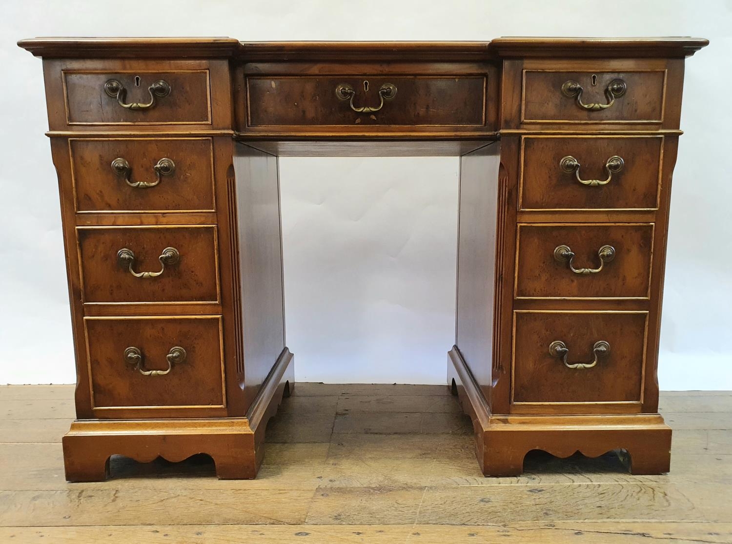 A modern walnut kneehole desk, having nine drawers, 113 cm wide Some small losses and wear to the