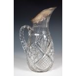 A cut glass water jug, with a German silver coloured metal mount, stamped .800, 31 cm high