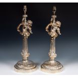 A pair of silver plated lamp bases, in the form of cherubs seated on a column, on round bases, 60 cm