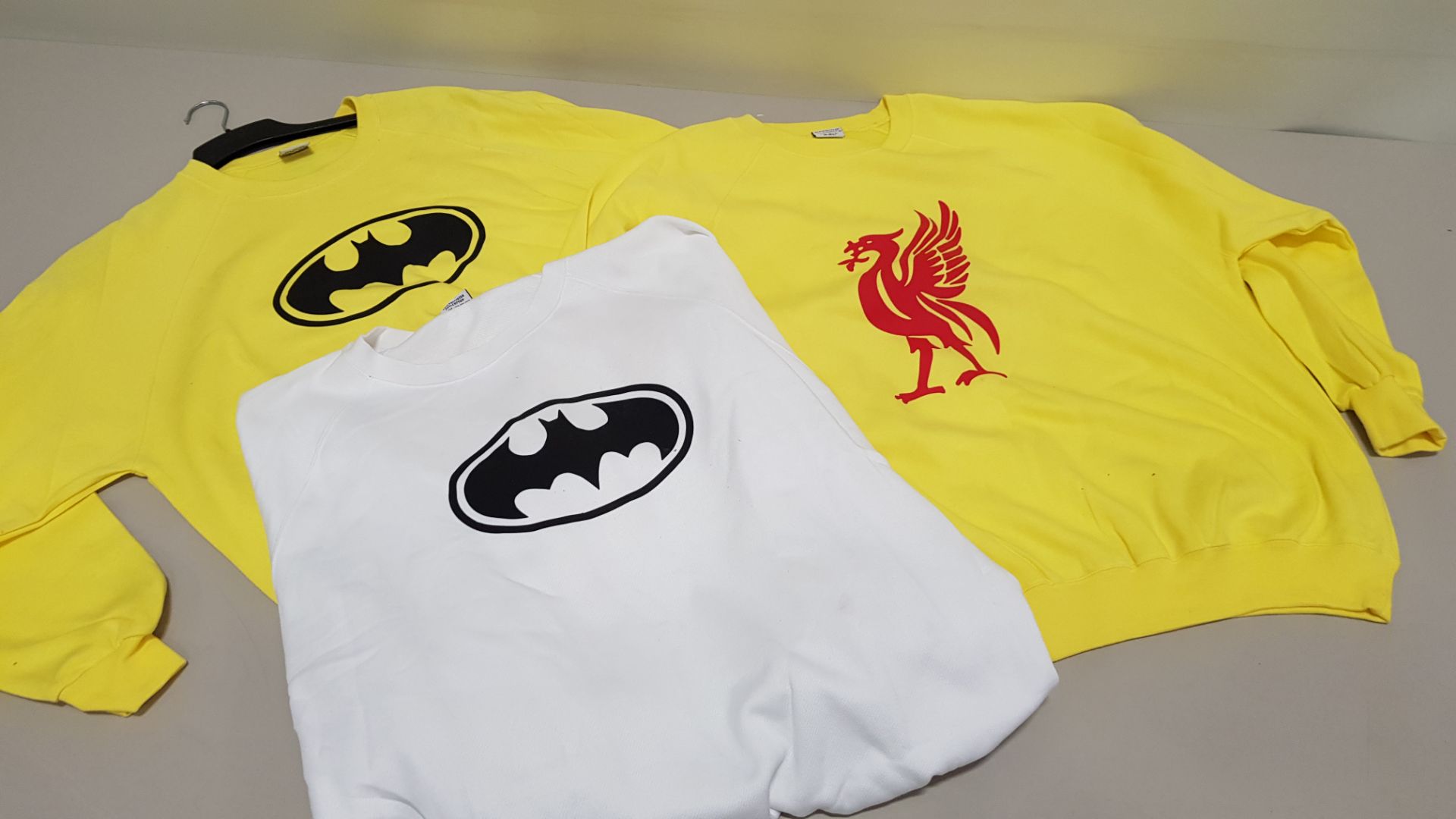 50 PIECE CLOTHING LOT CONTAINING YELLOW BATMAN JUMPERS, YELLOW LIVERPOOL JUMPERS AND WHITE BATMAN