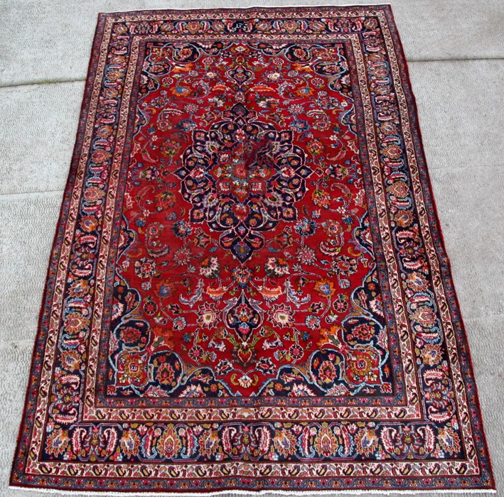 A Persian Mashad woollen hand knotted carpet with central floral medallion within floral borders