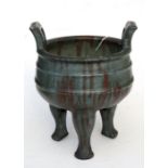 A Chinese two-handled pottery censer on three legs, multi-character seal mark to the underside,