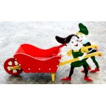 A novelty painted wooden wheelbarrow being pushed by two gnomes, 97cms (38ins) long.