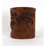 A Chinese carved and pierced bamboo brush pot decorated with figures seated at a table playing a