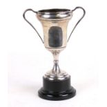 A silver two-handled trophy cup on an ebonised plinth, Birmingham 1938, overall 20cms (8ins) high.