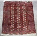 A Turkoman Bokhara rug with three repeated rows of guls with a geometric border, on a red ground,