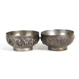 A pair of Indian metal bowls decorated in relief with various deities, 9cms (3.5ins) diameter.