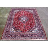 A fine Persian Mashad woollen hand knotted carpet with central floral medallion within borders on