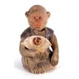 A Japanese pottery nodding figure in the form of a monkey holding a fan, 9cms (3.5ins) high.