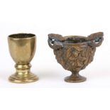 A small bronze Bacchanalain libation cup with fruiting vine decoration and ram's head handles,