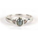 A 9ct white gold set with a central cats eye chrysoberyl cabochon flanked by two diamonds, approx UK