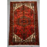 A Persian Hamadan hand knotted woollen rug with stylised central medallion and bird motifs within