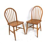 A pair of Ercol blonde elm stick back dining chairs with solid seats and tapering legs joined by