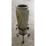 An Arts & Crafts wrythen form amphora pottery umbrella stand in a wrought iron tripod stand,